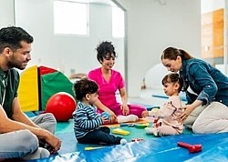 Eltern und ihre Kleinkinder sitzen auf dem Boden und spielen