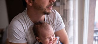 Vater hält schreiendes Baby im Arm