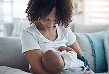 Mutter stillt Baby auf der Couch