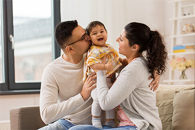 Mutter und Vater sitzen mit Baby auf Sofa