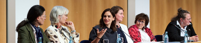 Personen sitzen bei einer Podiumsdiskussion zusammen