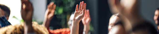 Teilnehmer einer Konferenz heben die Hände