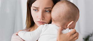 Erschöpfte und traurige Mutter mit ihrem Baby