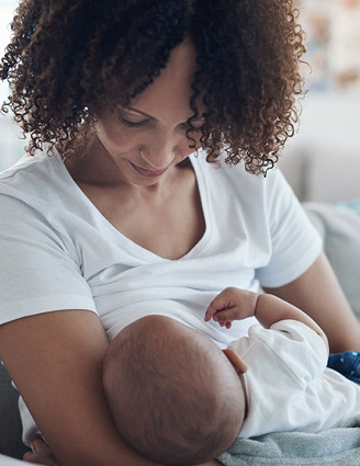 Mutter stillt Baby auf Couch