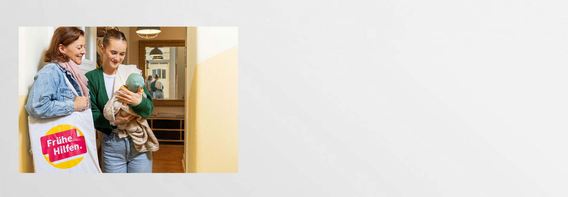 Willkommensbesuche in den Frühen Hilfen Junge Mutter begrüßt Besuchende der Frühen Hilfen an der Haustür und betrachtet mit ihr neutral das Baby